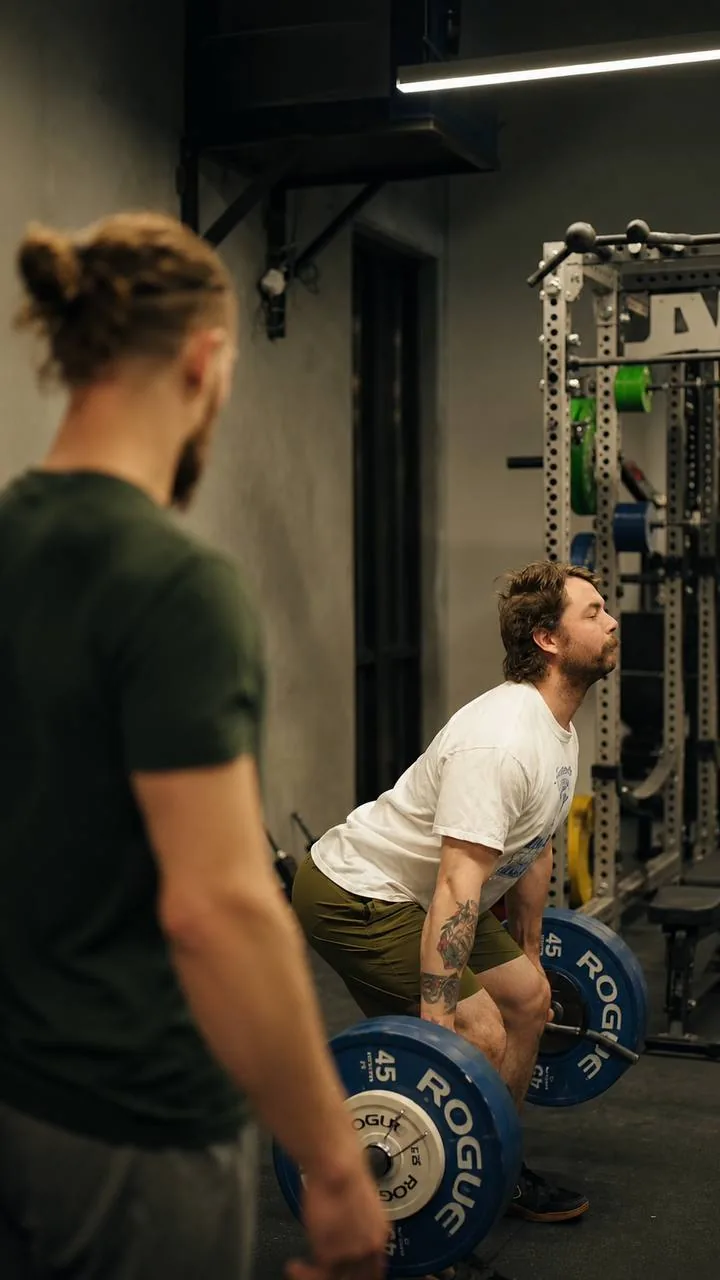 Coached strength training with a barbell deadlift